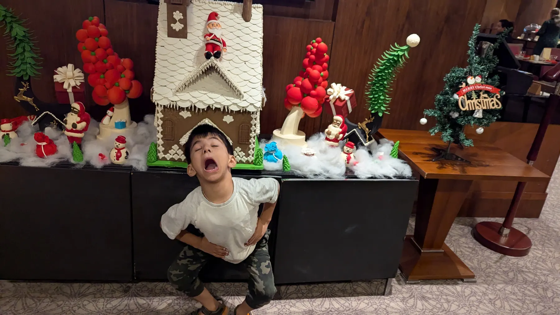 A boy pulling a face in front of a gingerbread Christmas display